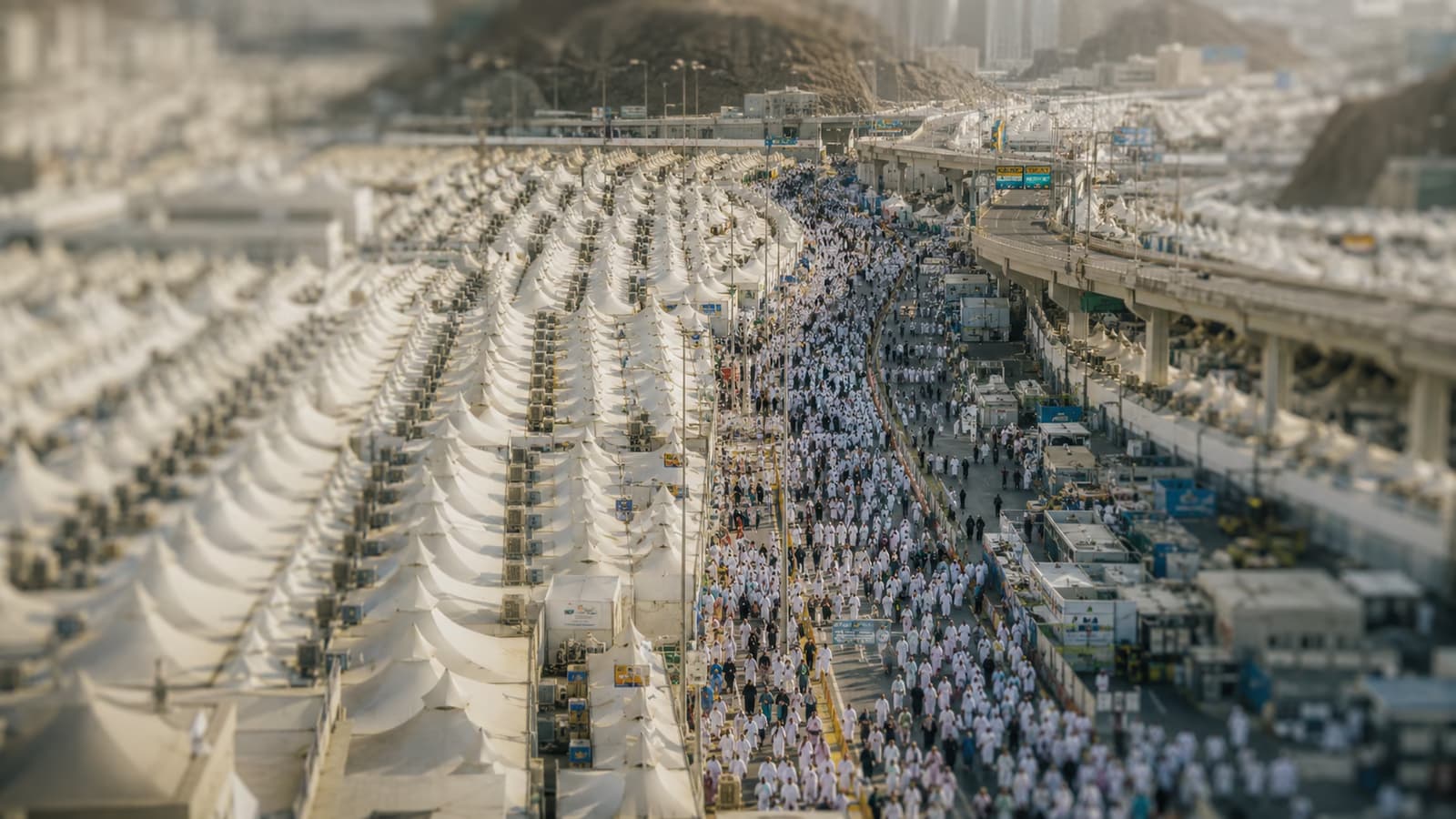 Pilgrims walking between rows of white tents in Mina